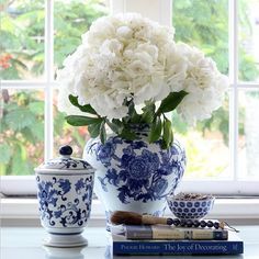 a blue and white vase sitting on top of a table next to a book shelf