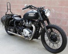 a black motorcycle parked next to a brick wall