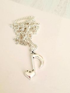 a silver necklace with a heart and a key hanging from it's side on a white surface