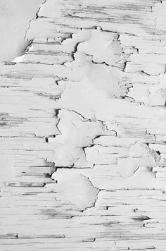 an old white paint chipped wall with peeling paint