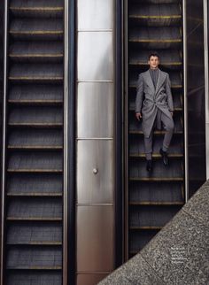 a man in a suit is standing on an escalator