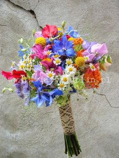 a bouquet of colorful flowers in front of a stone wall