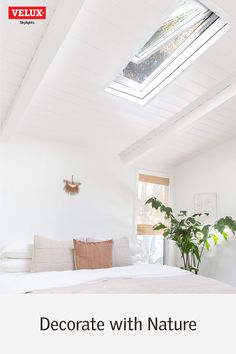 a bedroom with white walls and a skylight above the bed is furnished with natural materials