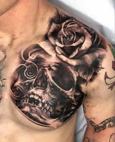 a man's chest with a skull and rose tattoo design on his chest,