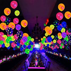 a room filled with lots of colorful balloons floating in the air over tables and chairs