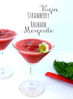 two glasses filled with strawberry rhubarb margaritas and garnished with a flower