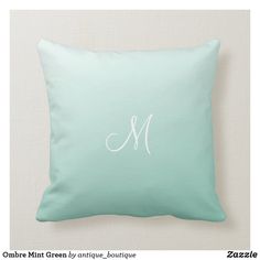 a mint green pillow with the letter m in white on top and an embroidered monogram