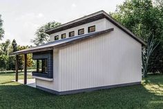 a small white building sitting on top of a lush green field in front of trees