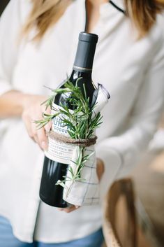 a woman holding a bottle of wine with a plant in it