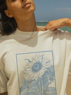 🌞Bring a touch of Dutch charm to your wardrobe with our Vintage Inspired Sunflower T-Shirt featuring the "Holland" text! 🌻 This tee combines the beauty of sunflowers with a vintage flair, perfect for anyone who loves floral designs and classic styles. Made from soft, high-quality fabric, it ensures comfort and style in one stunning package. Details: Material: 100% Cotton Sizes: XS,S, M, L, XL, XXL Care: Machine wash cold, tumble dry low Designed with love and crafted for comfort ❤️ Pair it with your favorite jeans, shorts, or skirts for an effortless, chic look. Whether you're exploring tulip fields or enjoying a sunny day out, this tee is your perfect companion. Order yours today and embrace the beauty of Holland! ✨ Floral Graphic Tee, White Graphic Tee With Sunflower Print, Sunflower Print Graphic Tee, Relaxed Fit Cotton T-shirt With Sunflower Design, Yellow Sunflower Print Graphic Tee, Casual Cotton T-shirt With Sunflower Print, Floral Graphic, Floral Designs, Favorite Jeans