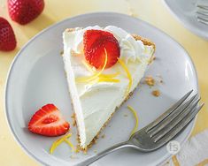 a slice of cheesecake on a plate with strawberries next to it and a fork