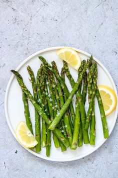 asparagus on a plate with lemon wedges