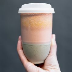 a hand holding a coffee cup in front of a gray background with speckles