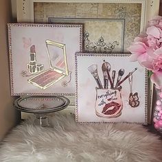 there is a vase with pink flowers on the shelf next to pictures and makeup brushes