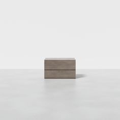 a small wooden box sitting on top of a white floor in front of a wall