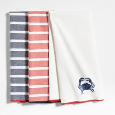 three towels with crab embroidered on them, one white and one red are folded next to each other