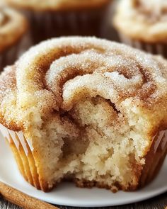 a close up of a muffin on a plate with cinnamon rolls in the background