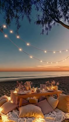 a picnic table set up on the beach at night with string lights strung over it