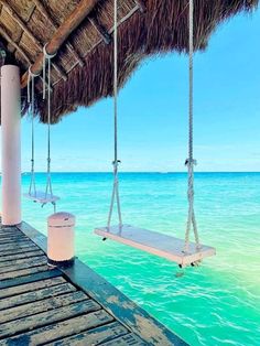 a wooden dock with two hammocks hanging from it's sides over the ocean