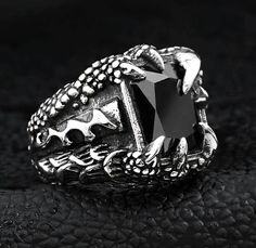 The arctic dig uncovered an ancient claw, wrapped around a brightly glowing gem. What became of the rest of the dragon that had treasured the enchanted stone, nobody knows... This beautifully detailed ring depicting a dragon's claw guarding its treasure. A unique piece is made of durable stainless steel, the ring is great for everyday wear or as a gift for loved ones. **Check the gallery for a ring sizing chart, or use this handy ring sizing/conversion tool** Materials: Stainless Steel, Cubic Zi Gothic Claw Rings As Gift, Collectible Dragon Design Jewelry Ring, Collectible Dragon Design Ring, Dragon Design Ring Jewelry Gift, Dragon Design Ring Jewelry For Gift, Black Fantasy Rings As Gift, Fantasy Style Black Ring For Gift, Black Fantasy Style Rings As Gift, Adjustable Gothic Snake Ring As Gift