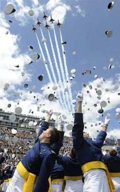 two men in blue and yellow uniforms are throwing white balloons into the air