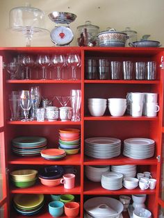 a red shelf filled with lots of plates and bowls on top of eachother