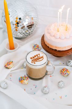 there is a cake with candles on it next to a cup of coffee and other confetti