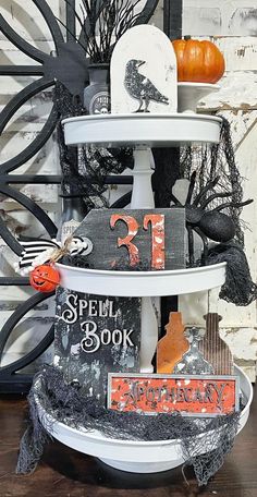 a three tiered halloween display with pumpkins and books on it's sides