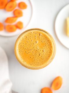 a glass of orange juice next to some sliced carrots on a white tablecloth