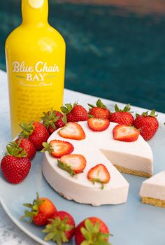 there is a piece of cake with strawberries on the plate next to it and a bottle of booze