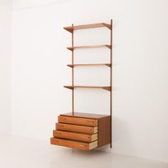 a book shelf with three drawers in front of a white wall and two shelves on each side