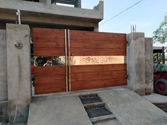 a large wooden garage door in front of a house with concrete walls and steps leading up to it