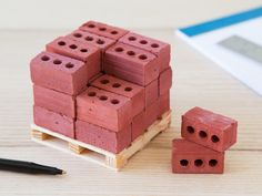 a stack of red bricks sitting on top of a wooden pallet next to a pen