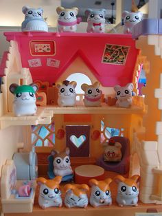 a toy house with lots of cats on the top floor and in front of it