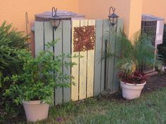 two potted plants sitting next to a wooden fence