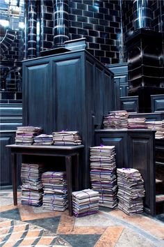 stacks of books are stacked on top of each other in front of a black cabinet