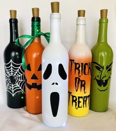 four halloween bottles with faces painted on them