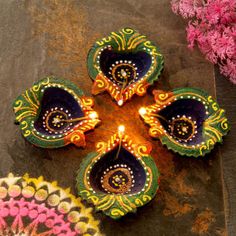 decorative diya with lights on the floor next to some pink flowers and petals in front of it