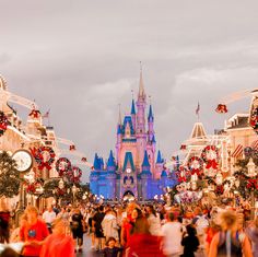 people are walking around in front of the castle at disney's christmas time parade