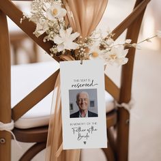 a card attached to the back of a wooden chair with flowers and ribbon around it