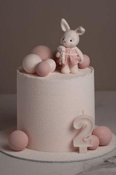 a birthday cake decorated with pink frosting and a bunny figurine on top