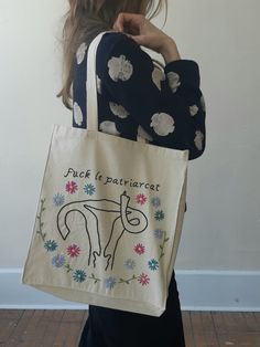 a woman carrying a tote bag with an image of a horse on the front