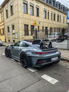 a grey sports car parked in front of a building