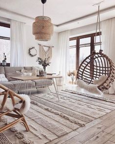 a living room filled with lots of furniture and hanging chairs in front of large windows