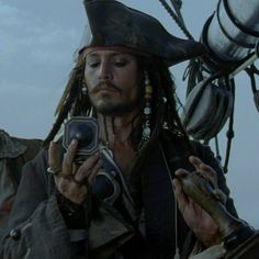 a man with dreadlocks holding a cell phone in front of a pirate ship