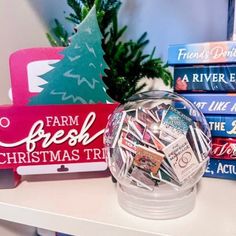 a glass bowl filled with lots of stickers next to a pile of books and a christmas tree