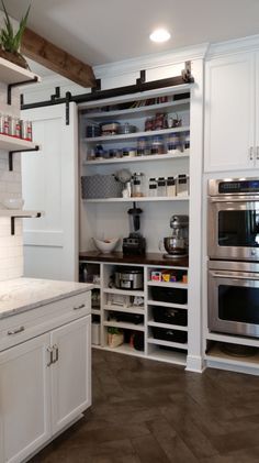 a kitchen with white cabinets and stainless steel stove top oven in the center, surrounded by open shelving