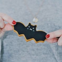 a woman holding a cookie shaped like a bat