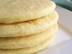 a stack of three white cookies sitting on top of a white plate next to a green container