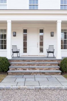 two chairs sitting on the front steps of a white house